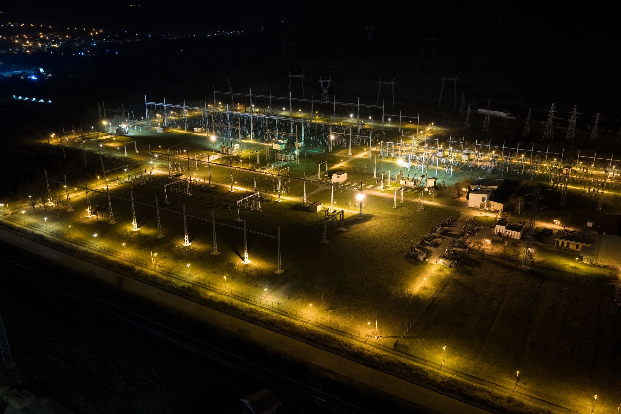 Illuminated electrical substation and transmission grid at night